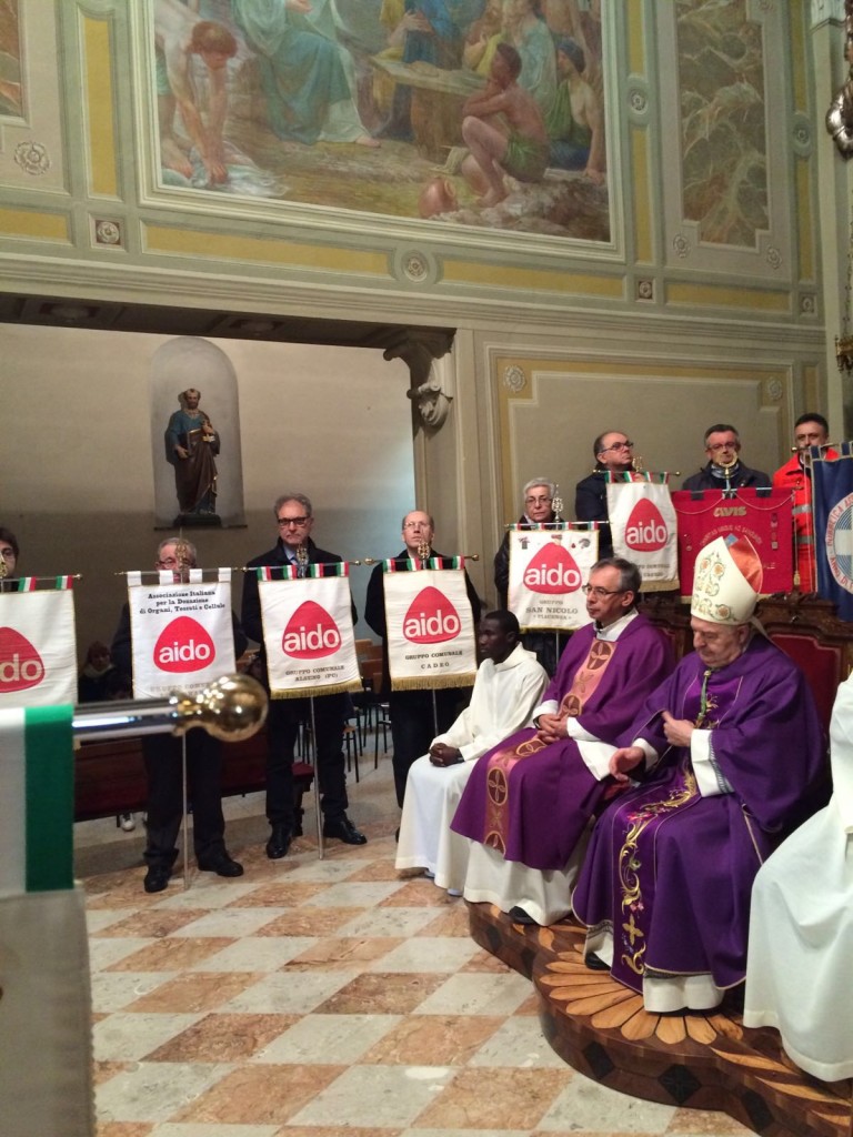 Monsignor Corbellini seduto a fianco di don Mauro. Attorno a loro i labari dei gruppi Aido della nostra provincia.